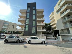dwa samochody zaparkowane na parkingu przed budynkiem w obiekcie Marina Dream Beach Apartments with Sea View Terrace - Agenzia Cocal w Caorle