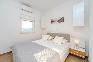 een witte slaapkamer met een bed en een raam bij La Vie luxury apartments with a pool in Stara Novalja