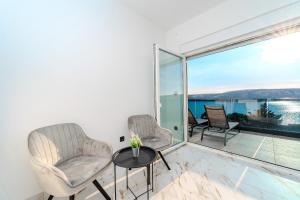 een woonkamer met 2 stoelen en een tafel en een groot raam bij La Vie luxury apartments with a pool in Stara Novalja
