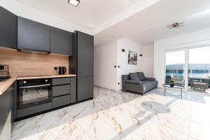 een keuken met zwarte kasten en een bank in een woonkamer bij La Vie luxury apartments with a pool in Stara Novalja