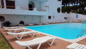 a swimming pool with chairs and a swimming pool at Pine Trees Penthouse in Olhos de Água