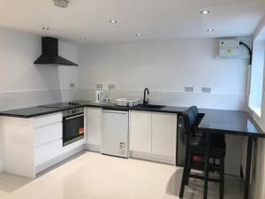 a kitchen with white cabinets and a black counter top at Garden studio in Golders Green