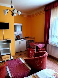 a living room with red chairs and a kitchen at Apart Júlia Villa in Hévíz