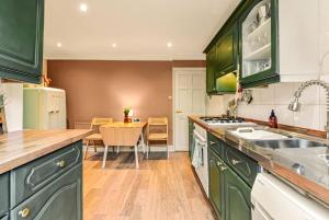 a kitchen with green cabinets and a dining table at Victorian cottage in Brixton! in London