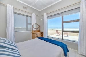 a bedroom with a bed and a view of the beach at Georgie in Agulhas