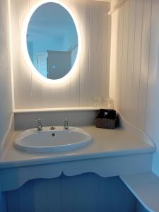 een badkamer met een wastafel en een ronde spiegel bij Fairwinds Guest Accommodation in Doolin