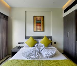 1 dormitorio con cama blanca y almohadas amarillas en Ariya Nivaas A Vegetarian Hotel, en Trivandrum