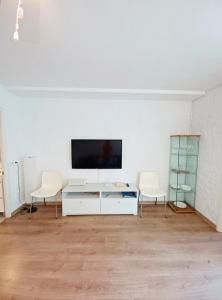 a living room with two chairs and a tv on a wall at Apt con piscina en Calella de Palafrugell, parking gratuito in Calella de Palafrugell