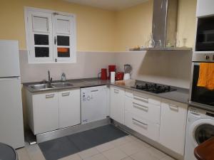 Una cocina con gabinetes blancos y un fregadero. en Sous le MAHOGANY, en Saint-Joseph