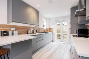 a kitchen with white cabinets and a wooden floor at Charlotte Cottage in Poole