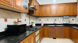 a kitchen with wooden cabinets and a black counter top at BluO Vasant Vihar PVR - Kitchen, Terrace, Lift in New Delhi