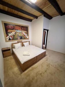 a bedroom with a large bed with a painting on the wall at Hotel Afsona old city in Bukhara