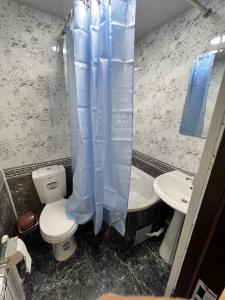 a bathroom with a toilet and a sink and a shower curtain at Hotel Afsona old city in Bukhara