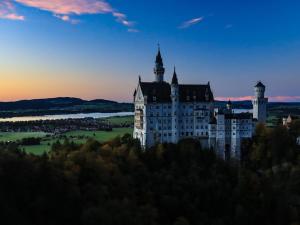 een kasteel op een heuvel met een zonsondergang op de achtergrond bij Gästehaus Köpf in Füssen