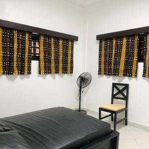 a room with a bed and a fan and a chair at Charly Arconville i in Abomey-Calavi