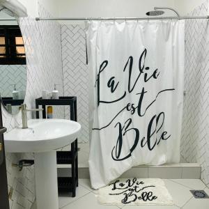 baño con cortina de ducha blanca y lavabo blanco en Charly Arconville i, en Abomey-Calavi