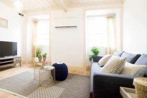 Una sala de estar con un sofá azul y un televisor. en Moeda ‘60 - Second Floor, en Coímbra