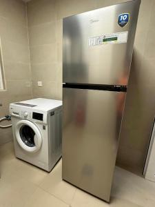 a refrigerator next to a washing machine in a kitchen at Palm Inn Hostel 2024 in Dubai