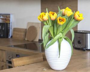OSTSEEPANORAMA Penth Nr 29 max 4 P في ديارهاجين: مزهرية بيضاء مليئة بالورود الصفراء على طاولة