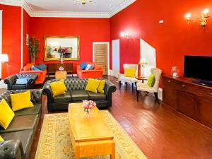 a living room with red walls and a couch and chairs at Harvieston Hall in Gorebridge