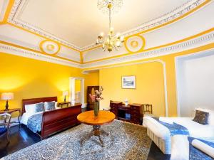 1 dormitorio con 2 camas, mesa y sofá en Harvieston Hall en Gorebridge
