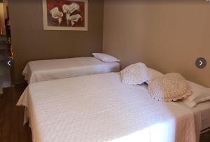 2 camas en una habitación con sábanas blancas en Estalagem do Carmo, en Pirenópolis