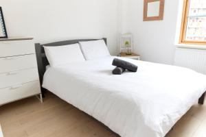 Una cama blanca con un animal de peluche negro. en Apartment with canal view in Broadway Market en Londres
