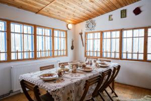 a dining room with a table and chairs and windows at Casa Plaiul Cailor: Rustic Mountain Hideaway in Proviţa de Sus +46 photos