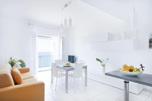 a white living room with a table and a couch at Vuelle Residence Apartments in Capo dʼOrlando