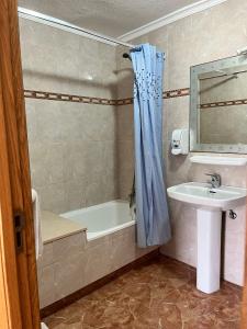 bagno con vasca, lavandino e tenda per la doccia di Hostería Somo a Somo
