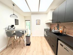 una cocina con encimeras negras, mesa y sillas en 4 Chambres - Grande Maison - Parking - Jardin, en Amiens