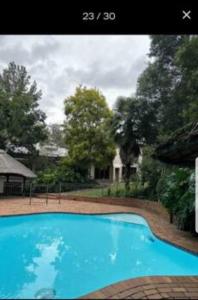 a large blue swimming pool in front of a house at 50 Arklow in Johannesburg