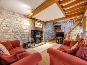 a living room with two couches and a stone wall at Capp Mill in Painswick