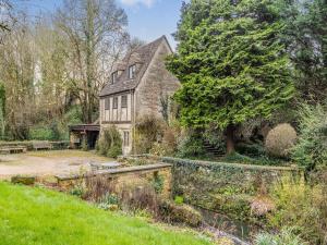 an old stone house with a garden and a pond at Capp Mill in Painswick