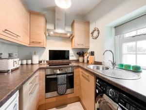 cocina con armarios de madera, fogones y fregadero en Southbank Cottage, en Errol