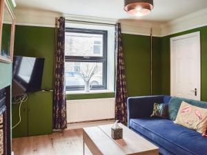 a living room with a blue couch and a window at The Bolthole in Bolton