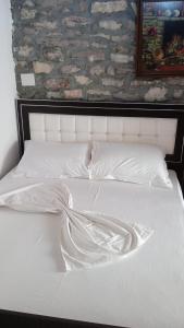 Cama blanca con sábanas y almohadas blancas en Karafil Guesthouse, en Gjirokastra