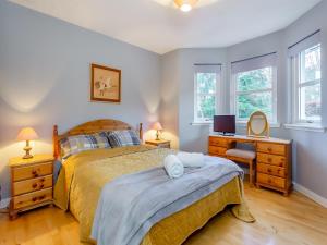 a bedroom with a bed and a desk and windows at Bluegrass Retreat On The River Ness in Inverness