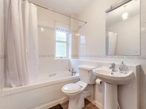 a white bathroom with a toilet and a sink at Bluegrass Retreat On The River Ness in Inverness