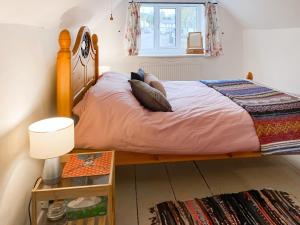 1 dormitorio con 1 cama con sábanas y almohadas rosas en Smithy End en Chard
