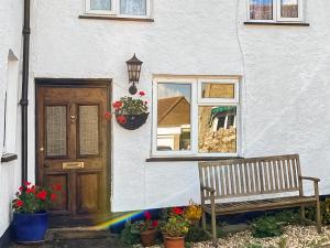 a bench in front of a house with a window at Smithy End in Chard