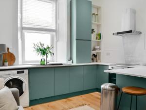 a kitchen with blue cabinets and a dishwasher at Main Street Flat C-uk46563 in Prestwick