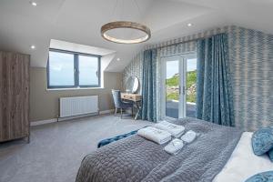 Schlafzimmer mit einem Bett, einem Schreibtisch und einem Fenster in der Unterkunft Goferydd, South Stack, Anglesey, 4 bed luxury home, hot tub, dog friendly in Holyhead