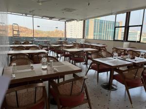 an empty restaurant with tables and chairs and windows at Swanotel Gachibowli in Gachibowli