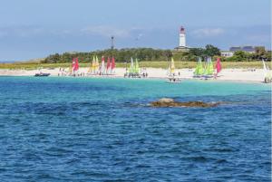 a beach with a group of sailboats and a lighthouse at L’Hermine, parking & terrasse in Concarneau