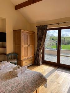 a bedroom with a bed and a sliding glass door at Neuadd Villa in Llanwnen