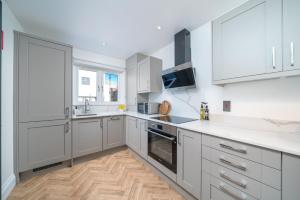 a kitchen with white cabinets and a wooden floor at Stylish 2 Bed Home in London -ExCel, City Airport* in London