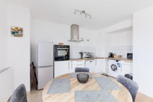a kitchen with a wooden table and a kitchen with white appliances at Confort Moderne Argenteuil – Proche Paris in Argenteuil +19 photos