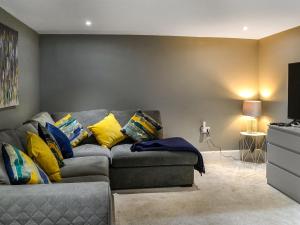 a living room with a gray couch with yellow pillows at Doodles Holiday Home in Eyemouth