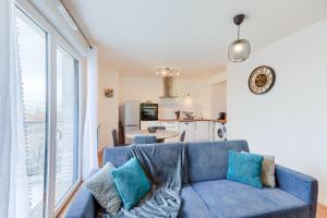 a living room with a blue couch and a kitchen at Confort Moderne Argenteuil – Proche Paris in Argenteuil